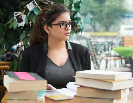 pensive female student sitting at table with books pensive female student sitting at table with books