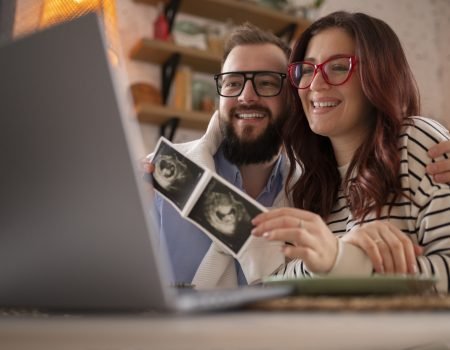 side view couple announcing pregnancy with laptop side view couple announcing pregnancy with laptop